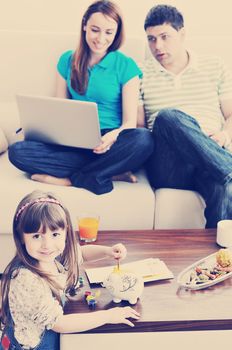 young happy family at bright and modern living room puting money in piggy bank and working on laptop computer on home finance