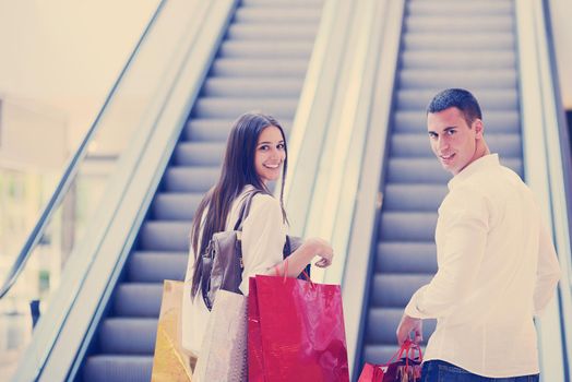 happy young couple with bags in shopping centre mall