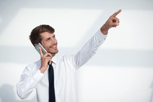 portrait businessman speaking on the phone celebrating with hand in the air and finger pointing up