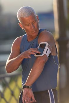 portrait of handsome senior jogging man while relaxing  and take break after morning run