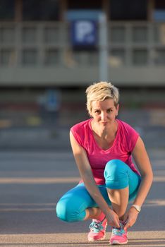 Closeup of jogging woman tying running shoe