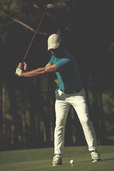 golf player hitting shot with club on course at beautiful morning