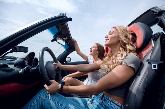 side view.two happy girls riding in the car.leisure, travel and people