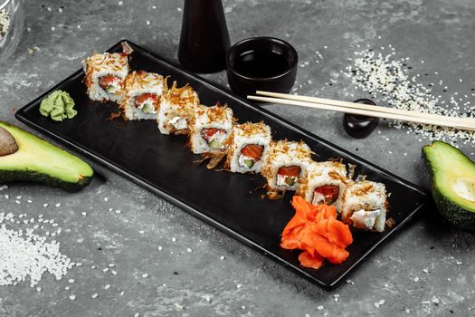 sushi rolls with cream cheese, fried salmon, tuna shavings or dried bonito, cucumber, nori. Chopsticks holding fresh katsuobushi roll in Japanese restaurant closeup.