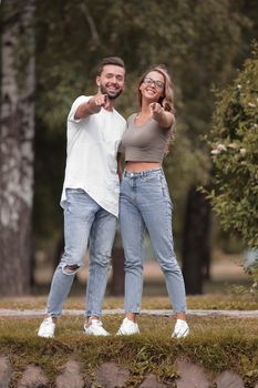 loving couple standing in the Park and pointing at you.photo with copy space