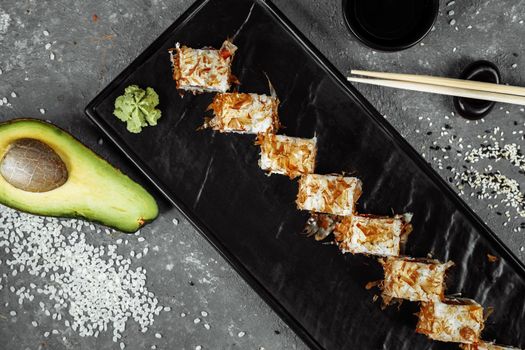 sushi rolls with cream cheese, fried salmon, tuna shavings or dried bonito, cucumber, nori. Chopsticks holding fresh katsuobushi roll in Japanese restaurant closeup.