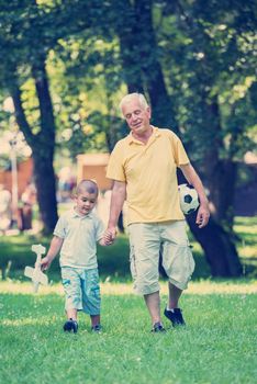 happy grandfather and child have fun and play in park on beautiful  sunny day