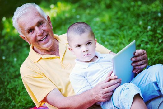 grandfather and child using tablet computer in park