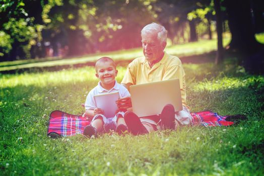 grandfather and child using tablet computer in park