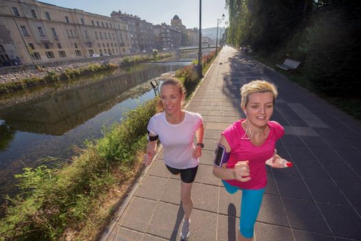 two middle aged female friends jogging have morning workout with sunrise in background