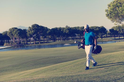 handsome middle eastern golf player carrying  bag  and walking at course to next hole