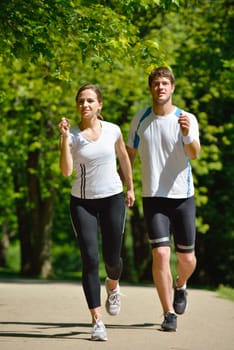 Young couple jogging in park at morning. Health and fitness.