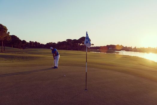 golf player hitting ball  with driver on course at beautiful sunset