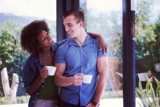 romantic happy young multiethnic couple enjoying morning coffee by the window in their luxury home