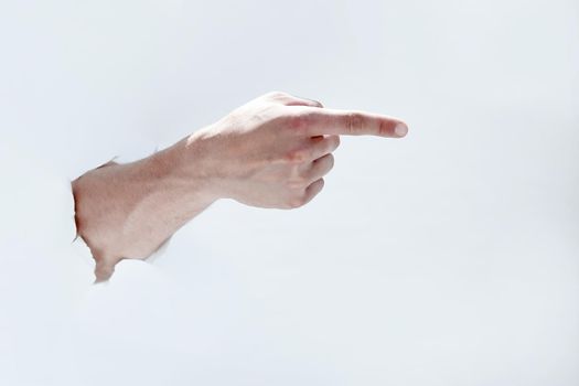 man hand breaking through the paper and pointing to a copy of the space.photo with space for text