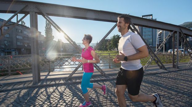 healthy mature couple jogging in the city  at early morning with sunrise in background