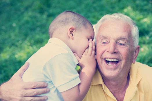 happy grandfather and child have fun and play in park on beautiful  sunny day