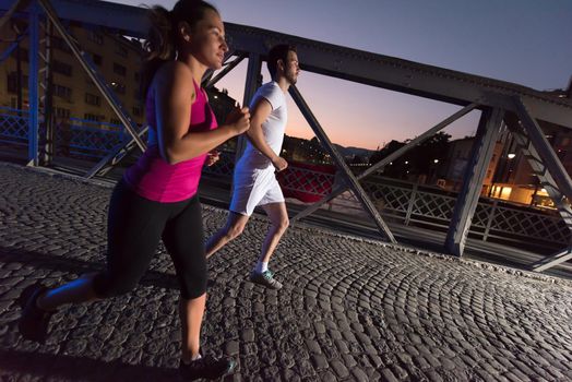 urban sports, healthy couple jogging across the bridge in the city at early morning in night