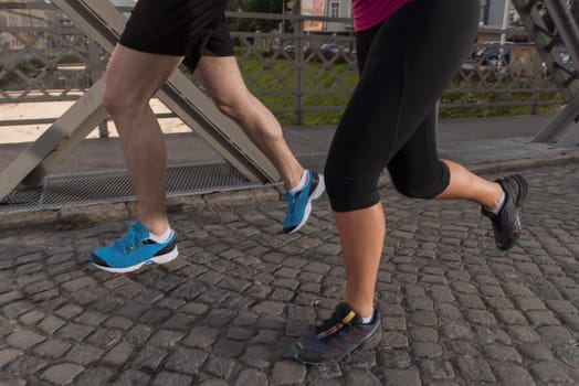 urban sports, healthy young couple jogging across the bridge in the city at sunny morning