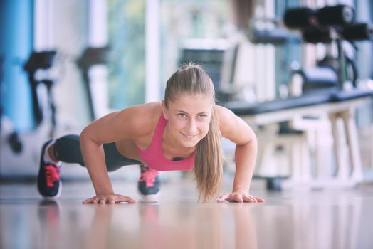 Gorgeous blonde woman warming up and doing some push ups a the gym