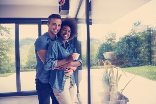 romantic happy young multiethnic couple enjoying morning coffee by the window in their luxury home