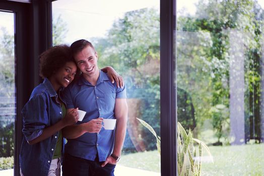 romantic happy young multiethnic couple enjoying morning coffee by the window in their luxury home