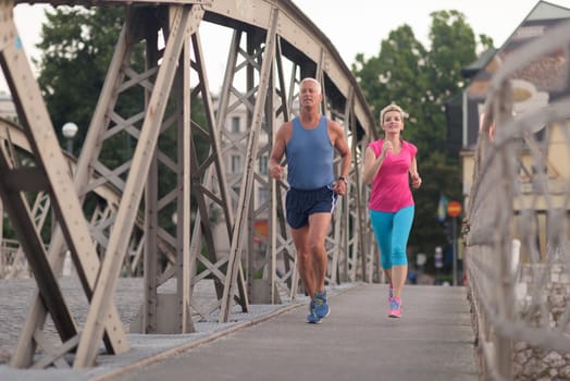 healthy mature couple jogging in the city  at early morning with sunrise in background