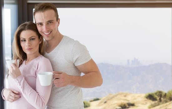 romantic happy young couple enjoying morning coffee by the window on cold winter day at home