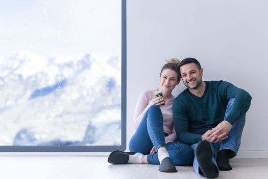 happy young couple sitting near window at home on cold winter day