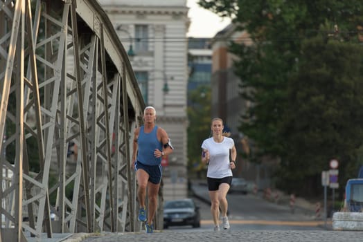 healthy mature couple jogging in the city  at early morning with sunrise in background