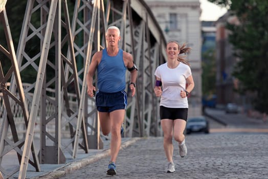 healthy mature couple jogging in the city  at early morning with sunrise in background