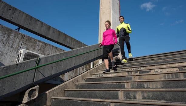 healthy young  couple jogging on steps  at early morning