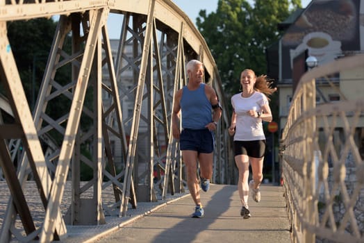 healthy mature couple jogging in the city  at early morning with sunrise in background