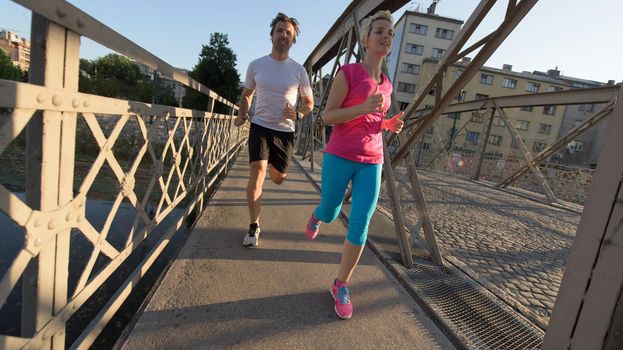 healthy mature couple jogging in the city  at early morning with sunrise in background