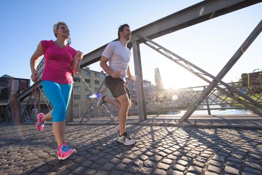 healthy mature couple jogging in the city  at early morning with sunrise in background