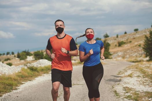 Couple running in nature at morning wearing protective face masks