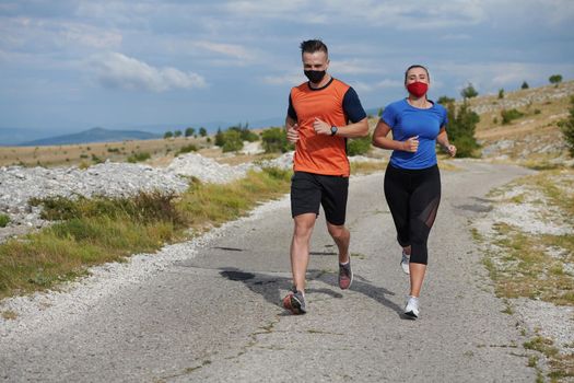 Couple running in nature at morning wearing protective face masks