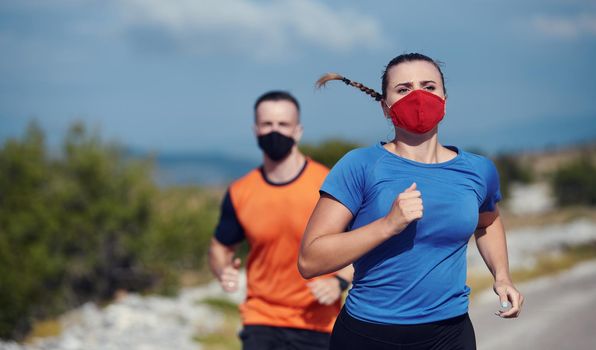 Couple running in nature at morning wearing protective face masks