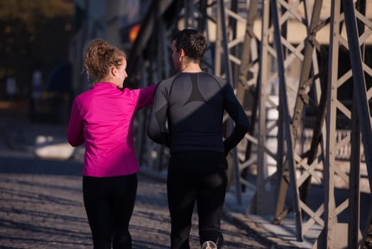 healthy young  couple jogging in the city  at early morning with sunrise in background