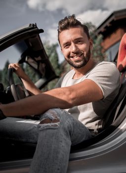 close up.handsome young man sitting in convertible car.the concept of a successful lifestyle