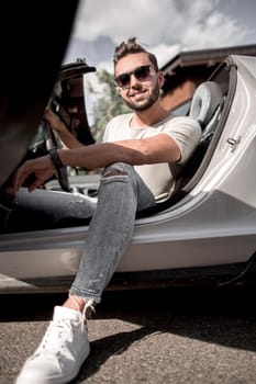 close up.successful young man sitting in a convertible car.the concept of lifestyle