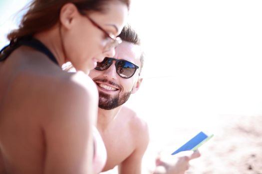 Romantic couple browsing the phone while on the beach,