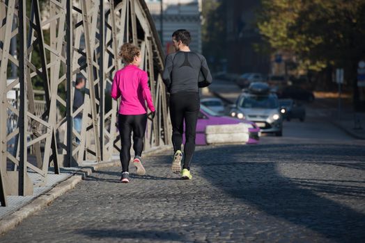 healthy young  couple jogging in the city  at early morning with sunrise in background