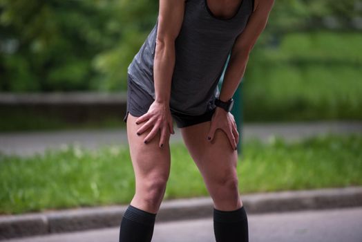 healthy female runner warming up and stretching in city park before morning training