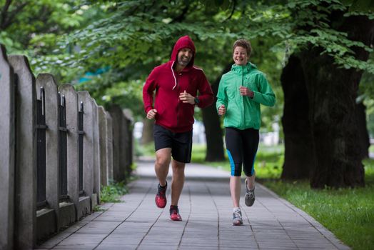 healthy jogging couple running in city park, runners team on morning training