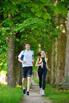 Young couple jogging in park at morning. Health and fitness.