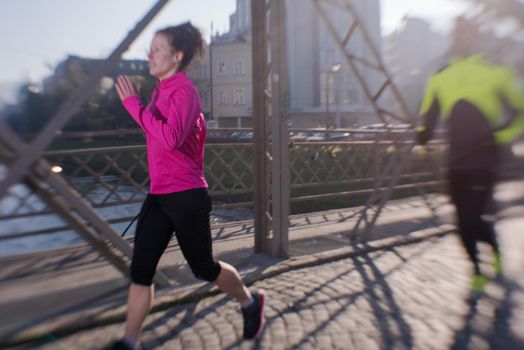 healthy young  couple jogging in the city  at early morning with sunrise in background