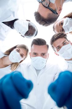 Team of medical professionals looking down at patient in surgical theater