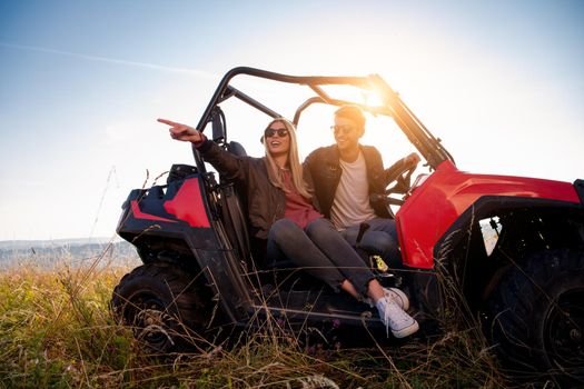 portrait of young happy excited couple enjoying beautiful sunny day while driving a off road buggy car on mountain nature