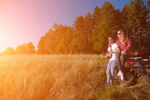 portrait of young happy excited couple enjoying beautiful sunny day while driving a off road buggy car on mountain nature